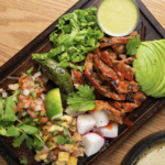 TACOS AL PASTOR ~ Garlic, chiles, cumin, pineapple, oregano, achiote marinated pork shoulder, served on a rustic oak board, with onions, cilantro, caramelized pineapple, avocado, fresh lime, Pico de Gallo, sliced radishes …and 5 tortillas on the side (build your own tacos).